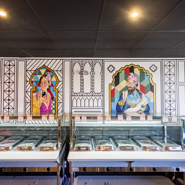 Restaurant buffet line with colorful murals of a woman and man in traditional attire.