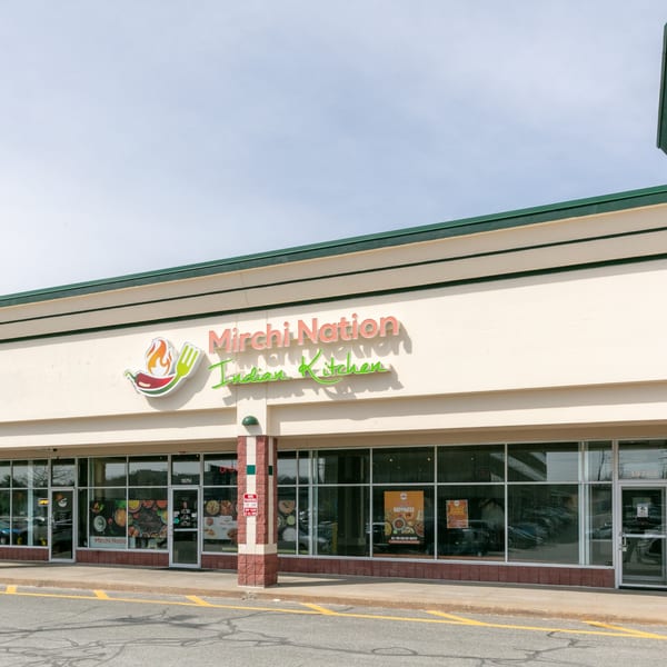 Exterior of Mirchi Nation Indian Kitchen, a restaurant with large windows and a prominent sign.